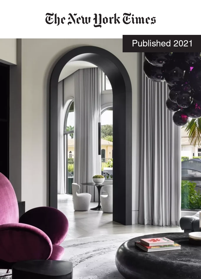 Modern interior design featuring a purple chair, stylish black coffee table with books, and elegant gray curtains framing a view of a lush outdoor space, highlighting a renovated living area in a Florida home.