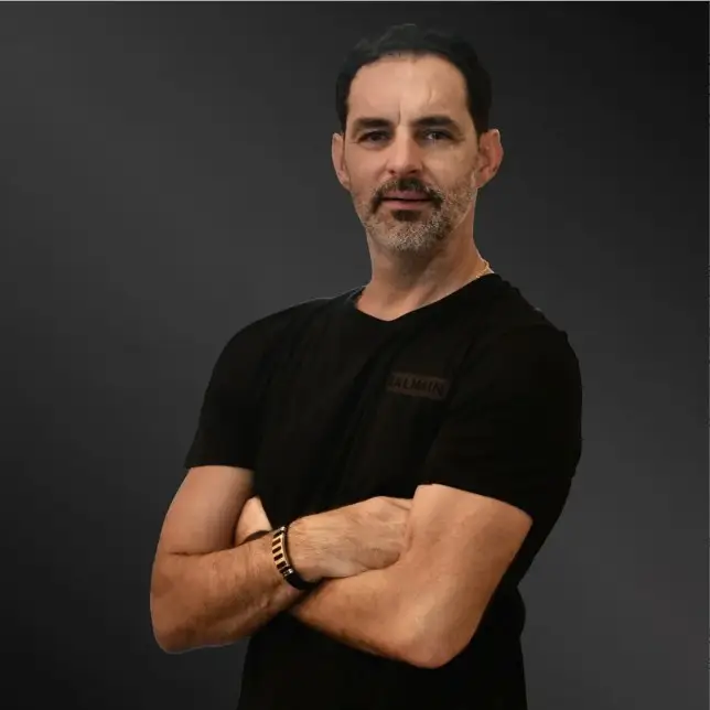 CoFounder and Managing Director of DeCoded International Group, Darek Homel, posing confidently with arms crossed against a dark background, representing expertise in custom millwork and decorative elements.